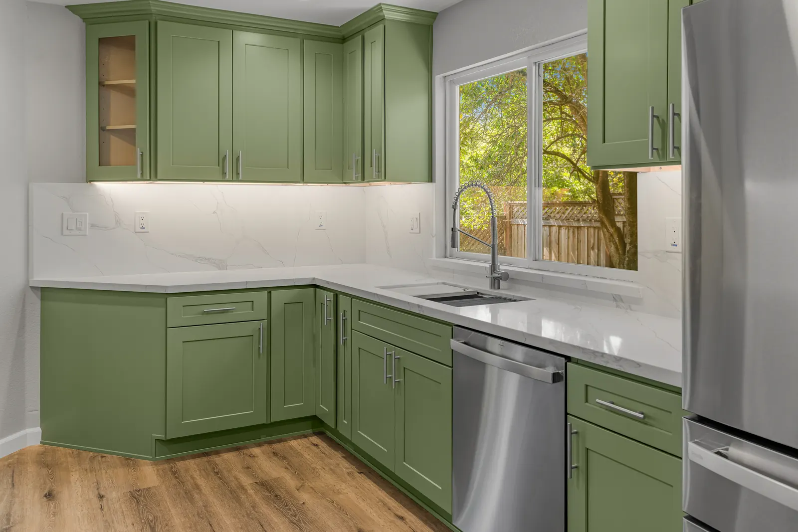 Green shaker cabinet kitchen with quartz counters and sink window