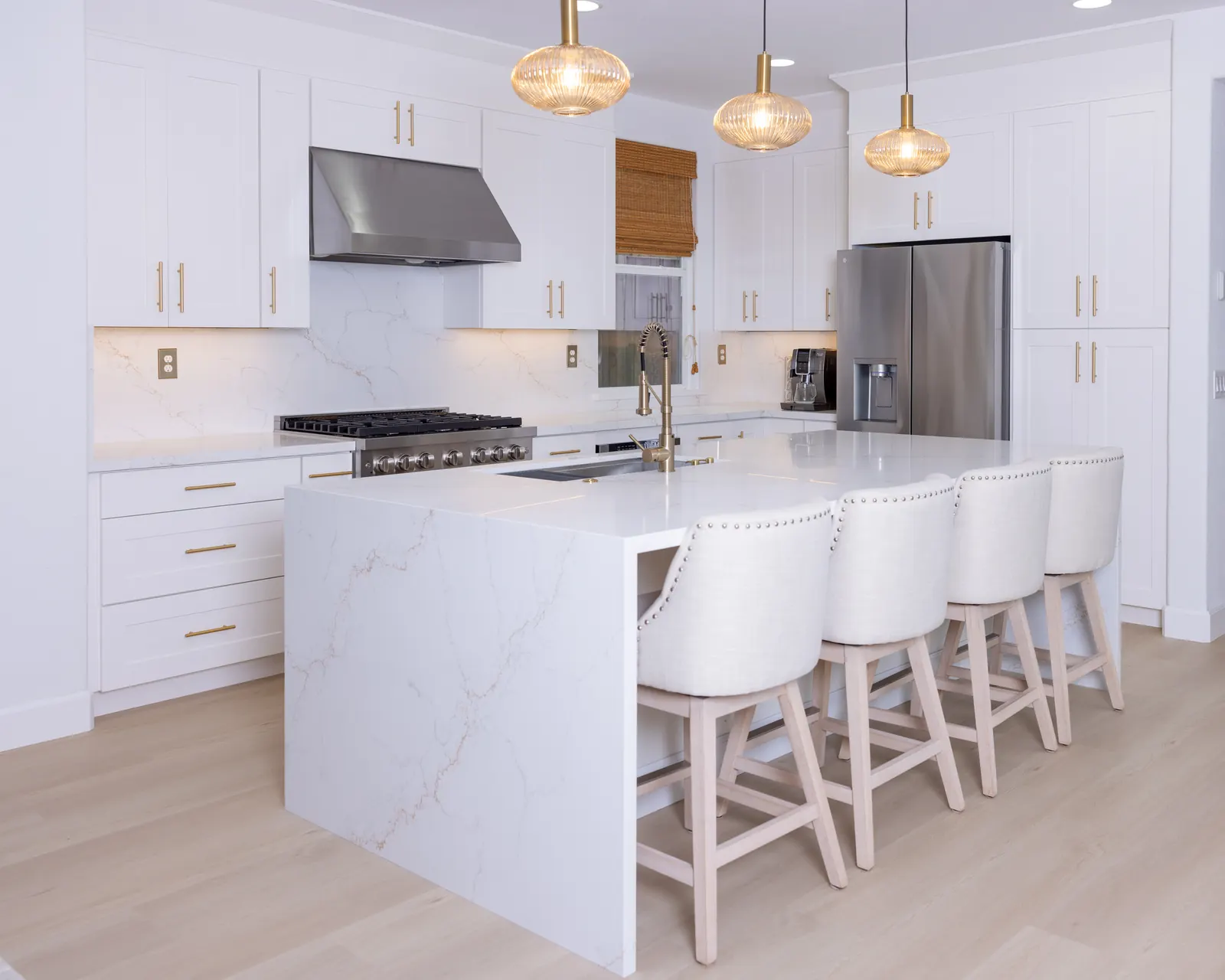 White kitchen island with quartz surface and pendant lighting